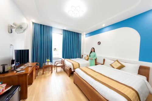 a woman standing in a hotel room with two beds at Homestay SUNA in Tuy Hoa