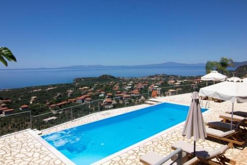 a swimming pool with chairs and umbrellas and the ocean at Irini Villa by Elrin Villas Mani in Neokhórion