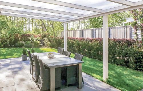 un patio con mesa y sillas bajo una pérgola en Oud Kempen Bungalow 183, en Stavenisse