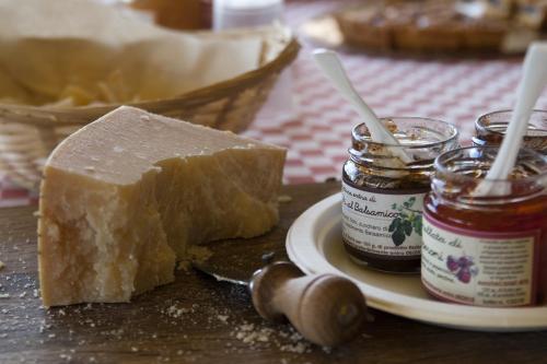 un trozo de queso en un plato junto a un frasco de miel en Agriturismo Bosco Del Fracasso, en Scandiano