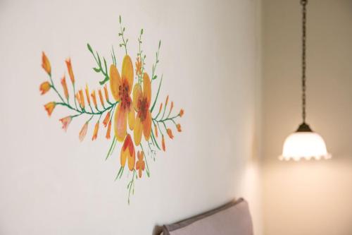 a painting of flowers on a wall next to a lamp at Teacher's House in Meganisi