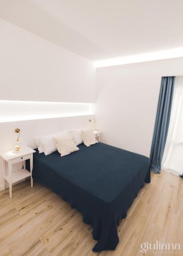 a bed in a white room with a black bedspread at Giuliana in Letojanni