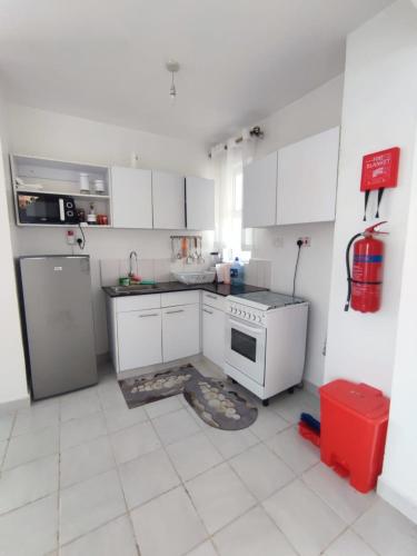 una cucina con mobili bianchi, fornelli e frigorifero di Emerano homes a Nairobi