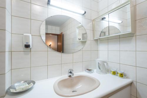 ein weißes Badezimmer mit einem Waschbecken und einem Spiegel in der Unterkunft Hostellerie Val Fleuri in Mersch