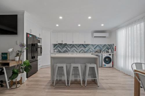a kitchen with a counter and stools in it at Driftwood Callala Plus - Jervis Bay Getaway - 10 Guests! in Callala Bay