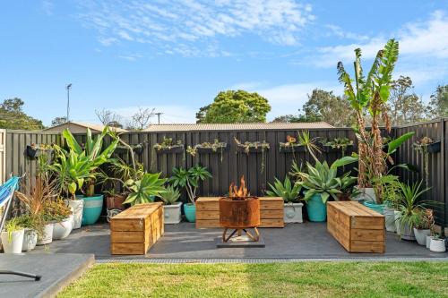 a backyard with a fire pit and potted plants at Driftwood Callala Plus - Jervis Bay Getaway - 10 Guests! in Callala Bay