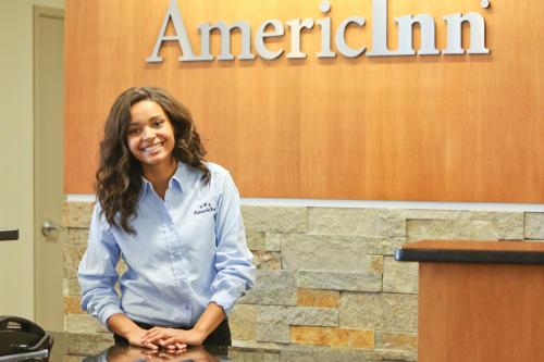 a woman is standing in front of a podium at AmericInn by Wyndham Wetmore Munising in Wetmore