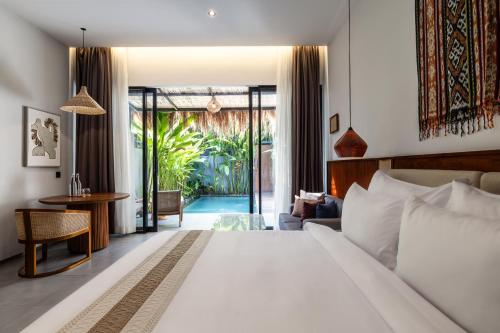 a bedroom with a large bed and a living room at The Clifton Canggu in Canggu