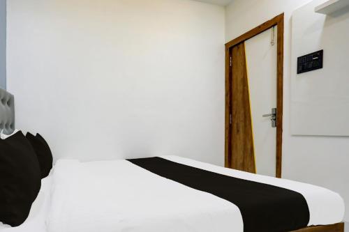a bedroom with a white bed and a door at HOTEL O ANUSHTHAN in Jabalpur