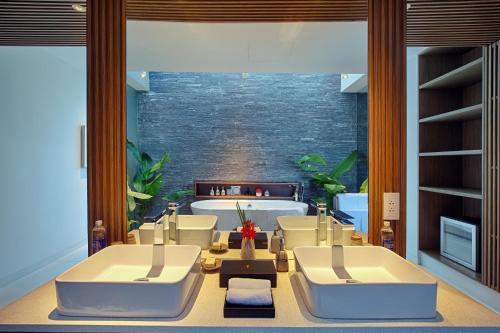 a bathroom with two white tubs and a bath tub at Naman Retreat in Da Nang