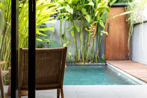 a chair next to a swimming pool with plants at The Clifton Canggu in Canggu