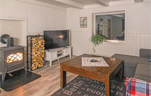 a living room with a couch and a tv and a table at Lovely Home In Vågstranda in Hjelvik