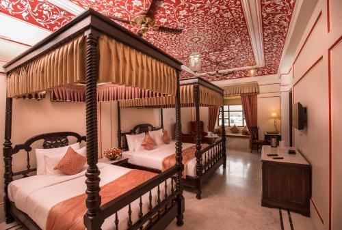a bedroom with four canopy beds in a room at Umaid Haveli-A Heritage Style Hotel & Resort in Jaipur