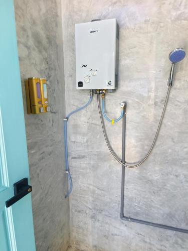 a shower in a bathroom with a hose attached to a wall at The Starry Dome Couple Room in Cameron Highlands