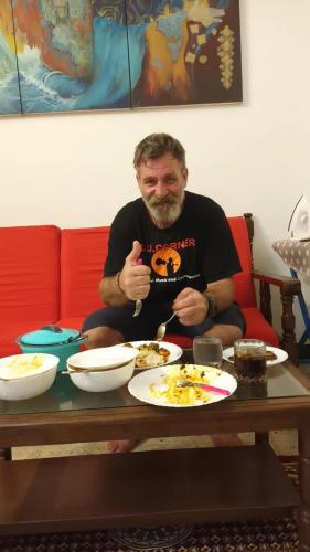 a man sitting at a table with plates of food at Villa Felicia 1BHk property with Kitchen and Modern Amenities in Puducherry