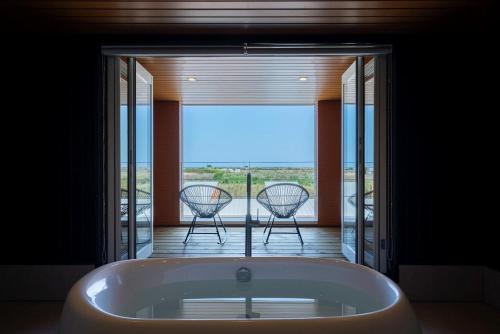 a bath tub in a room with a balcony with chairs at THE SECOND Chousei Beach Village 3階建てペット不可 in Jōnouchi