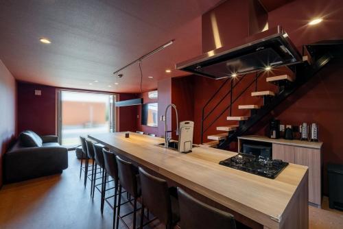 a kitchen with a bar with chairs and a staircase at THE SECOND Chousei Beach Village 3階建てペット不可 in Jōnouchi