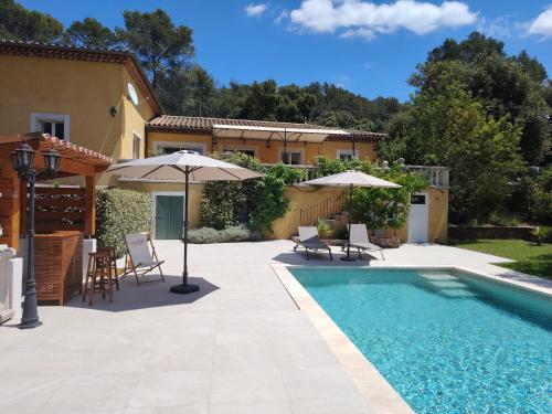 une piscine avec des parasols et une maison dans l'établissement Villa Xanadu, à Taradeau