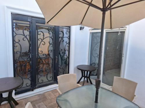 a glass table with an umbrella in front of a balcony at Casa de las Dunas in Ciudad Madero