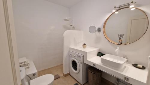 a white bathroom with a washing machine and a mirror at La Islita in Playa Blanca