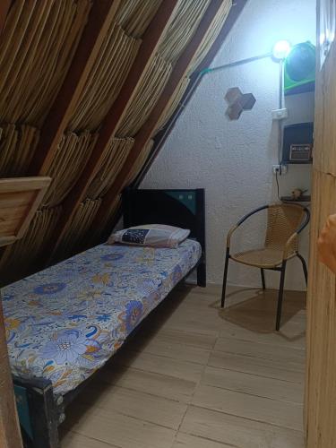 a small bedroom with a bed and a chair at Bio Coliving Tayrona in Santa Marta