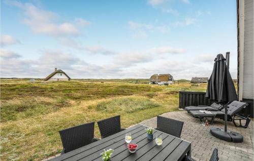 a patio with a table and chairs and a field at Holiday Home Hvide Sande With A Fireplace 05 in Bjerregård