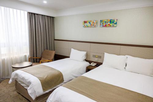 a hotel room with two beds and a chair at Jeju Robero in Jeju