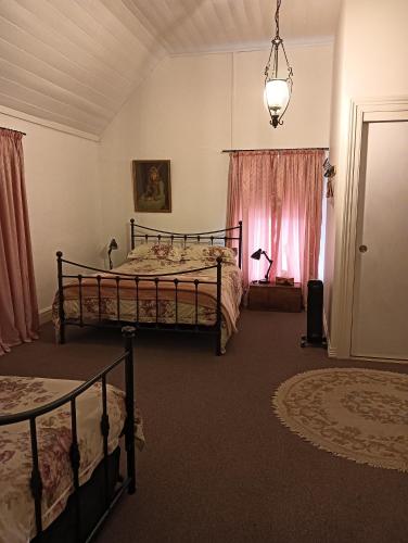 a bedroom with two beds and a chandelier at Old Colony Inn in New Norfolk