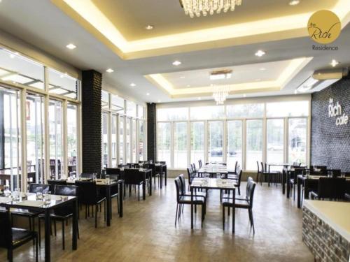 Un comedor con mesas y sillas y ventanas. en The Rich Residence, en Ban Tha Kup