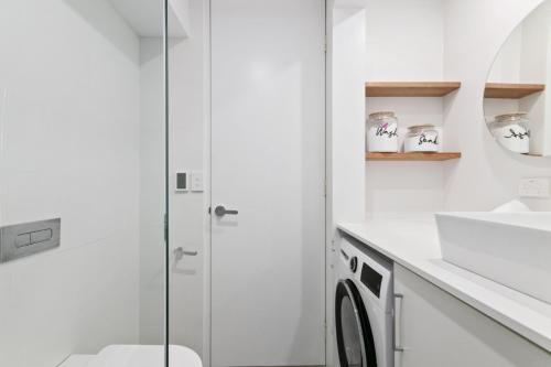 y baño blanco con ducha y lavadora. en Mowamba B4, en Thredbo