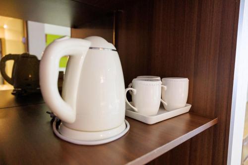 a white tea pot and two cups on a shelf at Jeju Robero in Jeju