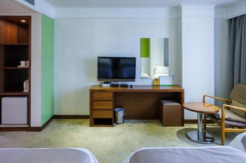 a room with a tv on a desk with a chair at Jeju Robero in Jeju
