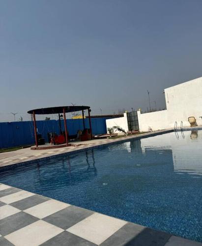 a large swimming pool with a checkeredkered floor at Honey Villa 3bhk With Private Swiming Pool in Mānakpur