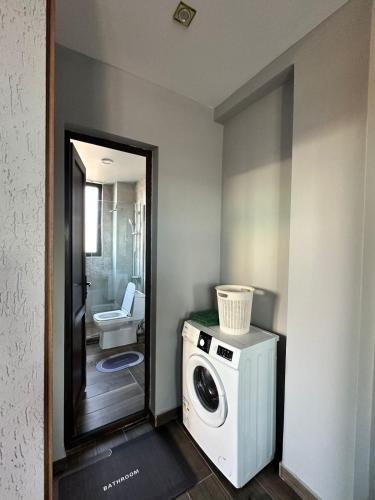 a bathroom with a washing machine and a toilet at Aparthotel Alfa in Ureki