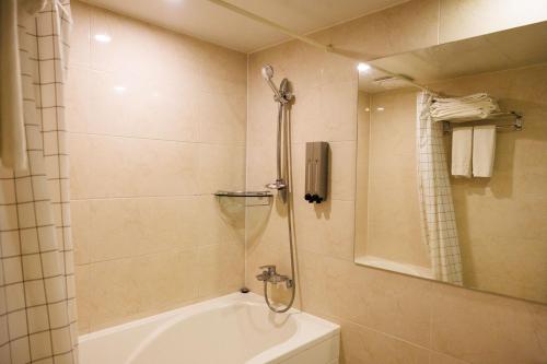 a bathroom with a shower and a tub and a toilet at Jeju Robero in Jeju