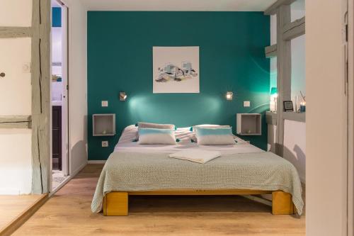 a bedroom with a bed with a blue wall at Grand studio Colmar Centre in Colmar