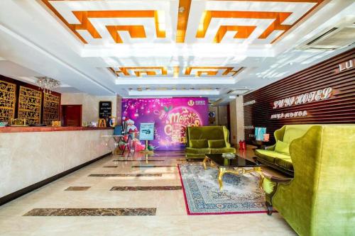 a lobby with green chairs and a pink wall at Zhongshan Louis Hotel in Zhongshan