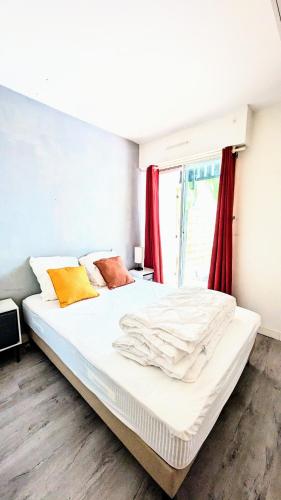- une chambre avec un grand lit blanc et des rideaux rouges dans l'établissement Le Petit Nid, T2 Rez de jardin avec parking - Plage et commerces à 15 à pied, à Villers-sur-Mer