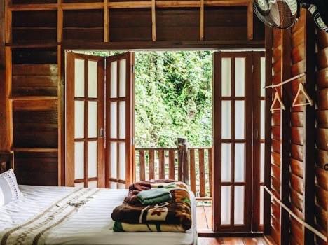 a bedroom with a bed and a large window at ไชยพล โฮมสเตย์ หมู่บ้านแม่กำปอง in Ban Pok Nai