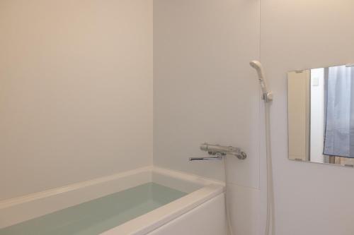 a white bathroom with a tub and a mirror at Komorebi in Tokyo