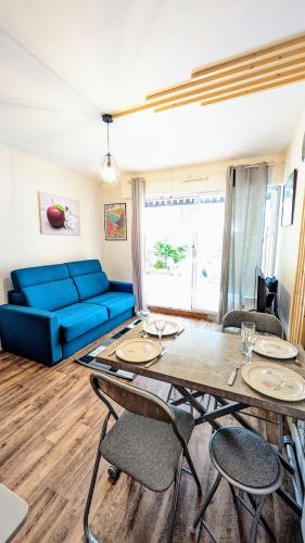 un salon avec un canapé bleu et une table dans l'établissement Le Petit Nid, T2 Rez de jardin avec parking - Plage et commerces à 15 à pied, à Villers-sur-Mer
