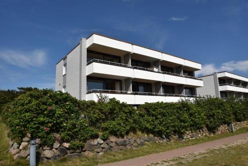 a white building with bushes in front of it at Haus Calma App 7 in Wenningstedt