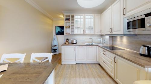 a kitchen with white cabinets and a sink at Haus Calma App 7 in Wenningstedt