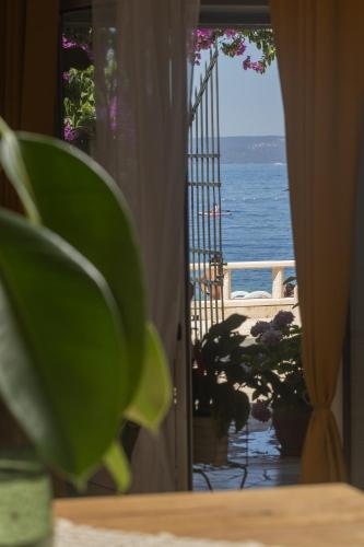 a door to a balcony with a view of the ocean at Beach APARTMENT in Podgora