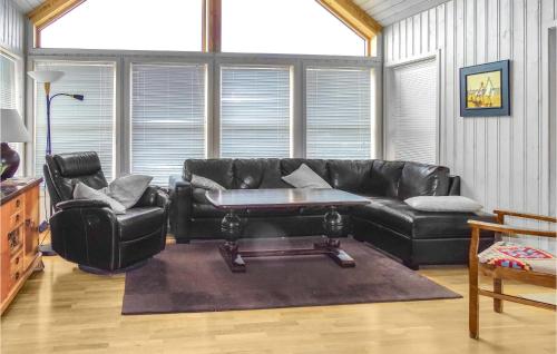 a living room with a black leather couch and a table at Five-Bedroom Holiday Home In Vikesa in Hovland