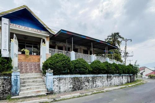 a building on a street with a stone wall at Hotel Harapan Isyes Syariah RedPartner in Parapat