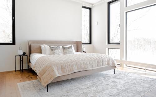 a bedroom with a bed with white walls and windows at Hiiragi by H2 Life in Niseko