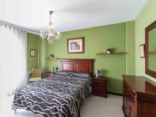 a bedroom with a bed and green walls and a chandelier at Casa La Palmera in Dúrcal