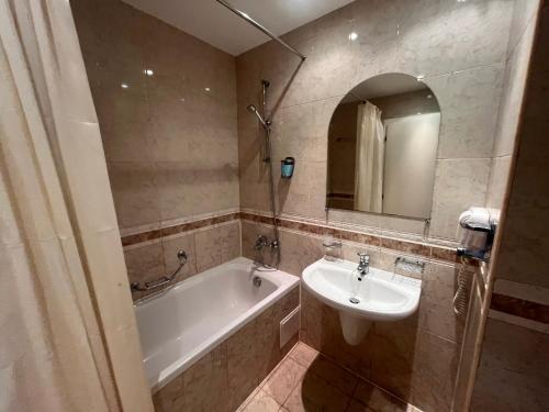 Un baño con lavabo, bañera y espejo. en Miramar Front Beach Self Catering Apartments No Swim Pool Access, en Sunny Beach
