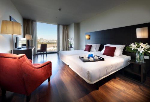 a bedroom with a large bed with a table and chairs at Eurostars Zaragoza in Zaragoza